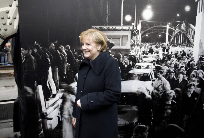 Pred padcem Berlinskega zidu je bila Angela Merkle širši javnosti neznana vzhodnonemška znanstvenica. 9. novembra 1989, ko so vzhodnonemški komunisti odprli mejo z Zahodno Nemčijo, je proti mejnim prehodom drla množica Vzhodnih Nemcev. Med njimi je bila tudi Merklova. Ta je najprej šla na svojo redno četrtkovo savno, nato pa namesto na pivo odšla skupaj z množico Vzhodnih Berlinčanov v Zahodni Berlin skozi mejni prehod na Bornholmer Strasse. Po kratkem obisku Zahodnega Berlina se je še isti dan vrnila v Vzhodni Berlin. Na fotografiji: Merklova ob 20. obletnici t. i. padca Berlinskega zidu stoji pred fotografijo, posneto 9. novembra 1989 na Bornholmer Strasse. | Foto: Guliverimage/Vladimir Fedorenko